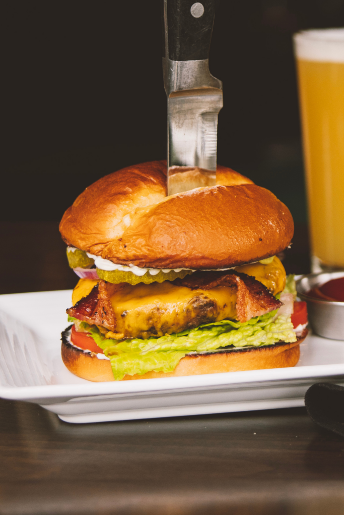 Stanford's Burger on a plate with a knife piercing through it.